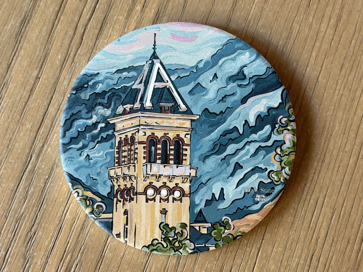 Round stone coaster featuring a towered university building illustration on blue waves