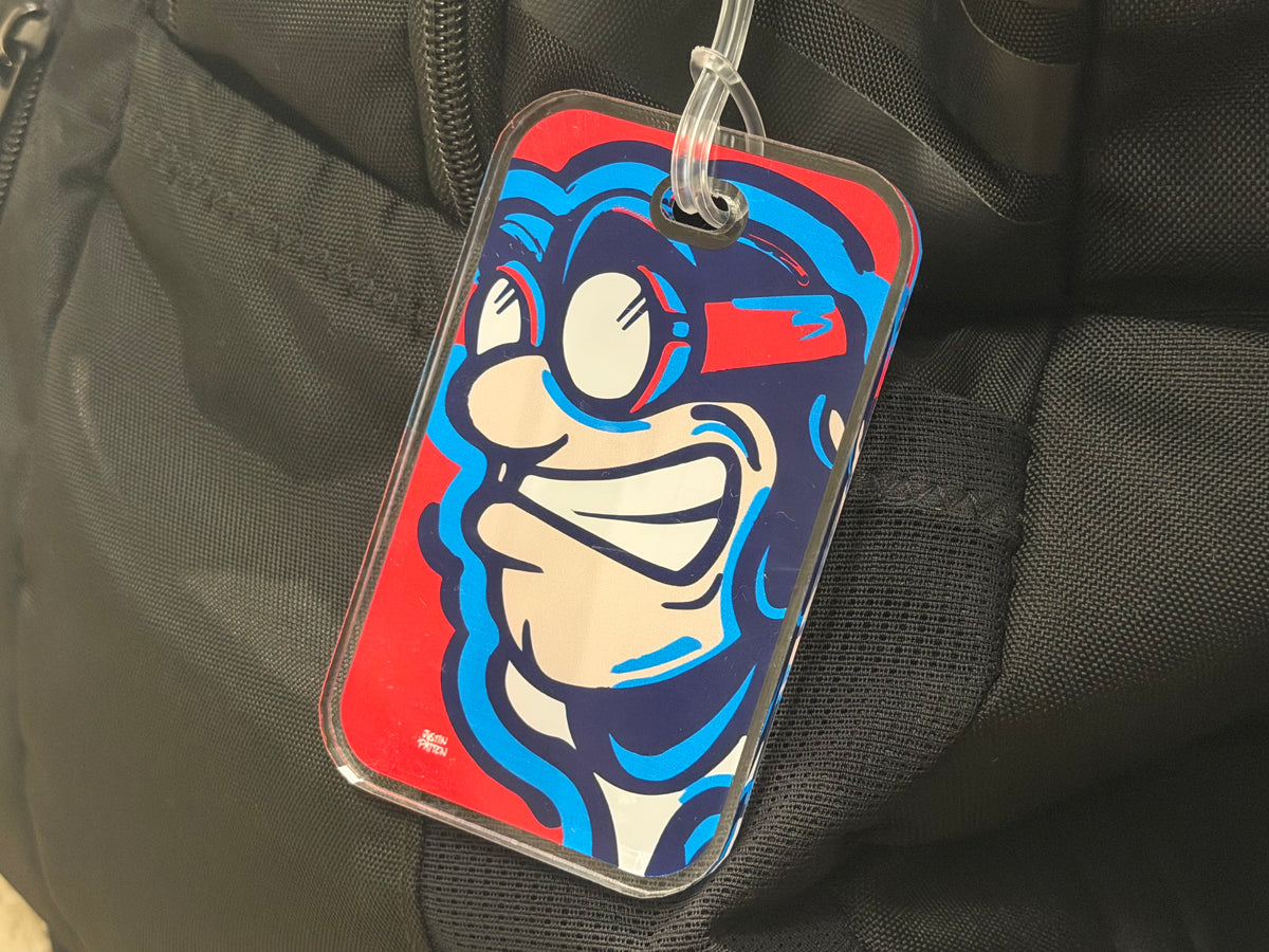 Clear plastic bag tag with Rudy Flyer cartoon face, attached by loop and ring