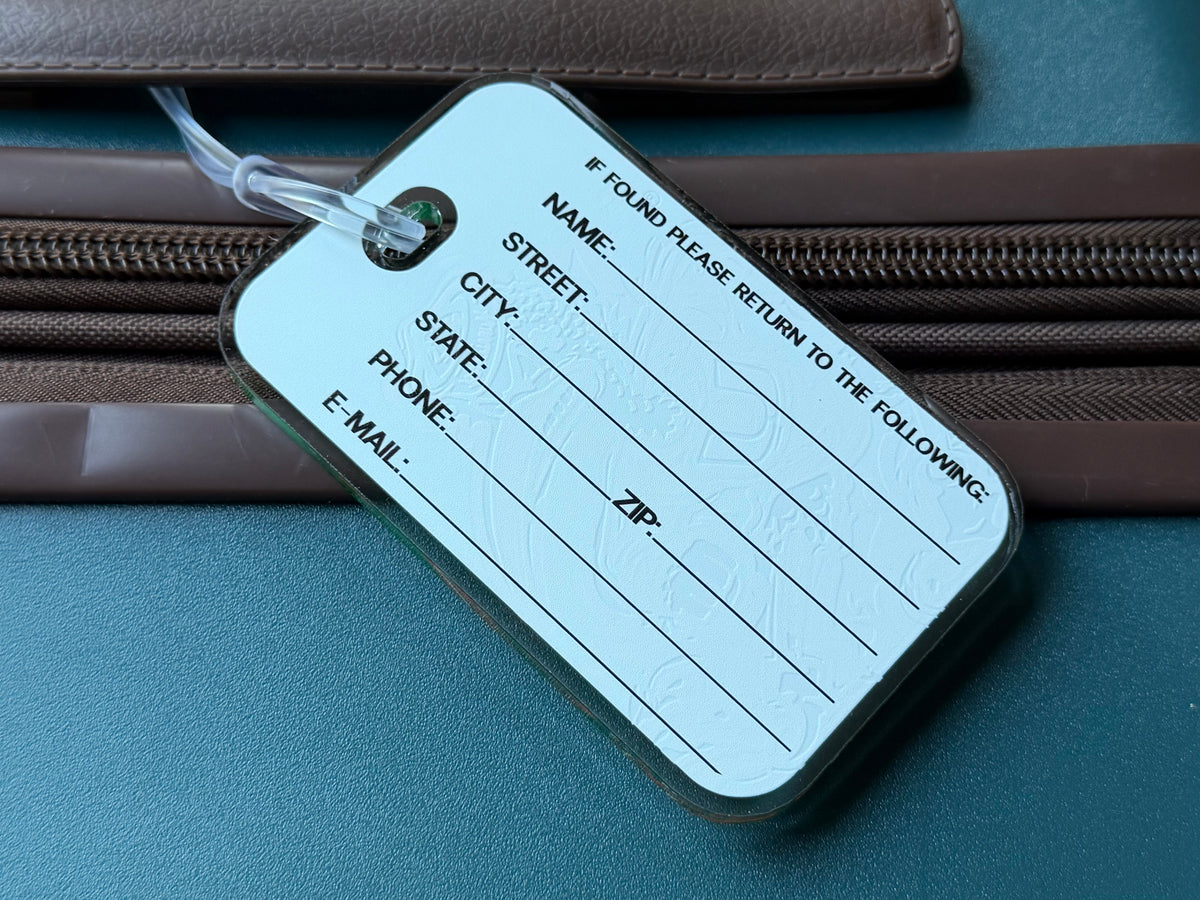 White return-address bag tag with 'IF FOUND PLEASE RETURN' and lined fields.