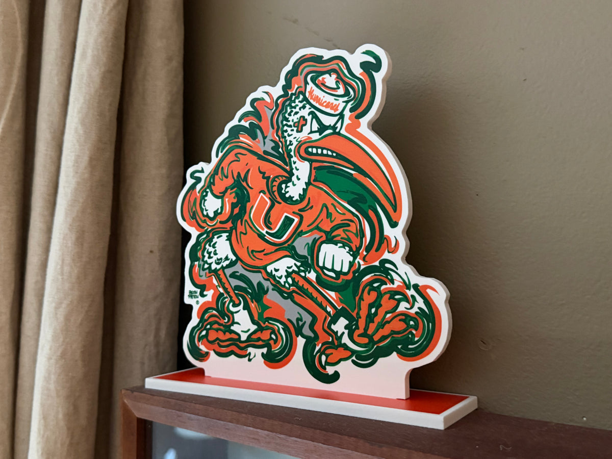 Miami Hurricanes mascot standee cutout on red platform, orange and green clawed eagle