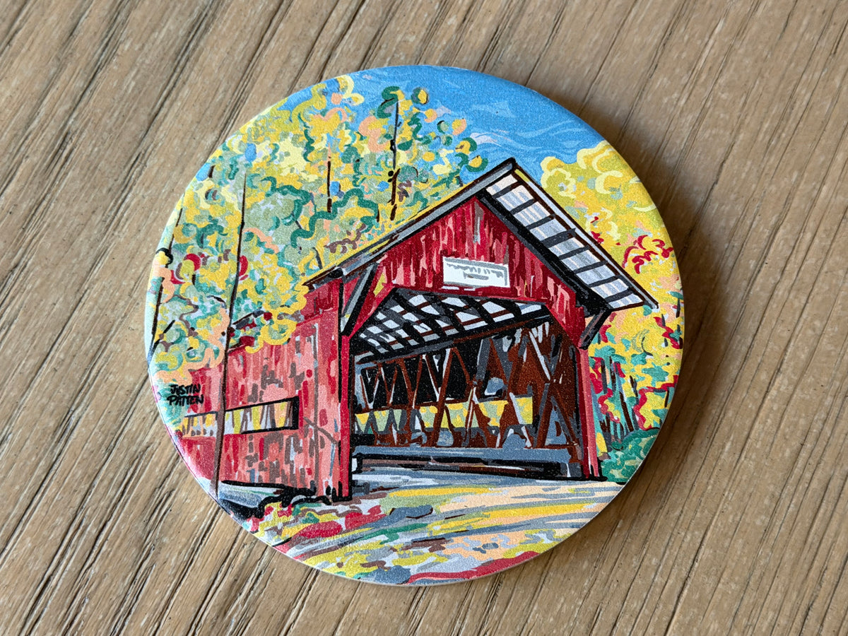 Round stone coaster with vibrant covered bridge illustration
